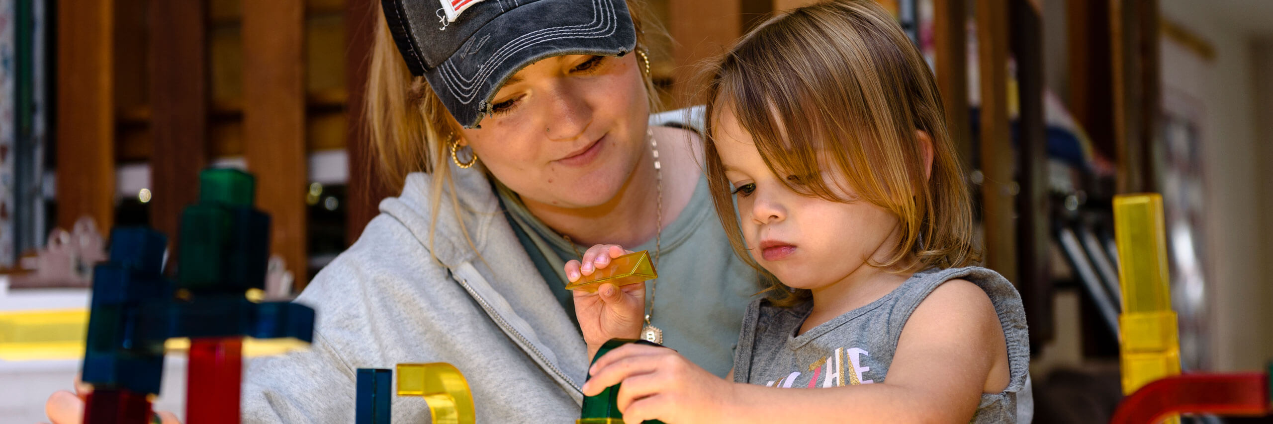 A staff members helps a child build with blocks.