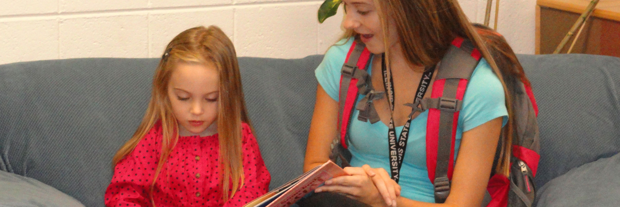 Woman reading a book with a little girl.